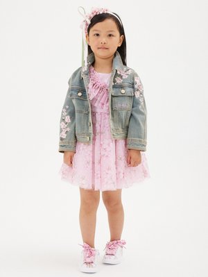 Giacca di denim con ricami floreali, vestito di tulle rosa con motivo floreale e sneakers bianche con lacci rosa. Accessorio per capelli floreale incluso.