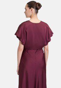 Burgunderfarbenes Satin-Kleid mit kurzen, puffigen Ärmeln und glatter Textur; verfügt über einen Reißverschluss auf der Rückseite und eine taillierte Taille, die zu einem leicht auslaufenden Saum führt.