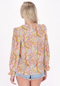 Blusa multicolore con motivo paisley in rosa, giallo e blu. Include dettagli arricciati sulle spalle e maniche lunghe. Tessuto morbido.