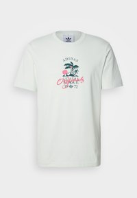 Biała koszulka Adidas z grafiką palmowy w zielonym kolorze, różowym okręgu oraz napisem "Adidas Originals Leisure League 1972" na środku przodu.