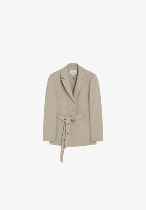Veste blazer beige cintrée avec revers crantés, deux boutons et une ceinture assortie ornée d'œillets métalliques, présentée sur un fond blanc.