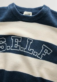 Tumesinine ja kreemjastriibuline sviiter, mille esiküljel on poolringina valgetes tikitud tähtedes sõna "S.E.L.F". Pehme tekstuur ja ümar kaelus.