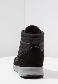 Černé vysoké tenisky s semišovým a syntetickým svrškem, texturovaným límcem kolem kotníku, kontrastní šedou podrážkou a bílým šitím.