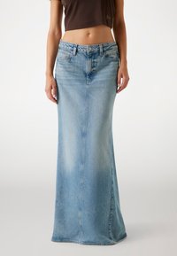Gonna di jeans lunga di colore azzurro chiaro, con taglio dritto, chiusura frontale con bottoni e lievi sbiaditure. Il materiale ha una consistenza liscia.