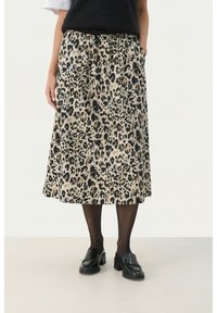 Jupe midi en imprimé léopard en tissu doux, dotée d'une taille élastique et de poches latérales. Associée à des mocassins noirs et des collants noirs transparents.
