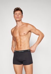 Schwarze Baumwoll-Boxershorts mit einer engen Passform, elastischem Bund mit "Calvin Klein"-Markenlogo und einer glatten Textur.