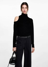 Črn kratek džemper s turtleneck ovratnikom in izrezom na enem ramenu, v kombinaciji z visokim črnim hlačami in majhno črno torbico.