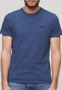Blauwe crew-neck t-shirt van een textuurstof met korte mouwen. Bevat een subtiele logo op de linkerkant van de borst. Casual pasvorm.