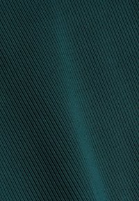 Tissu texturé bleu sarcelle avec des motifs nervurés verticaux, présentant une légère brillance et une apparence lisse, créant un effet riche et en couches.