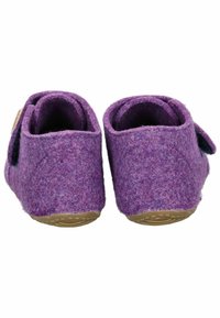 Fioletowe filcowe kapcie o miękkiej fakturze, z zaokrąglonym tyłem i regulowanym paskiem. Podeszwa jest w jasnobrązowym kolorze z wzorami zwiększającymi przyczepność.
