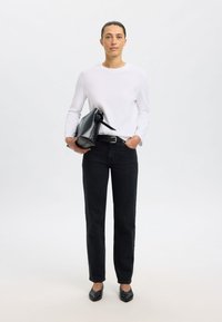 Weißes langärmliges Hemd, schwarze hoch taillierte Jeans, schwarze Handtasche und schwarze Ballerinas. Einfaches Design mit figurbetontem, geradem Schnitt.