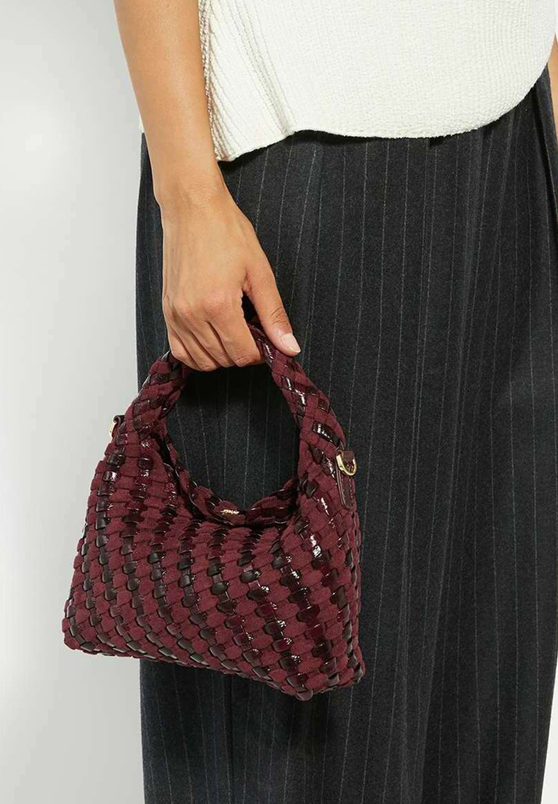Woven burgundy handbag with a textured surface, short handle, and glossy accents. Compact shape with a structured design.