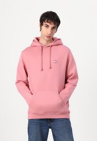 Felpa rosa con tasca a marsupio, cappuccio con coulisse e piccolo dettaglio del logo sul petto. Realizzata in tessuto morbido con una consistenza liscia.