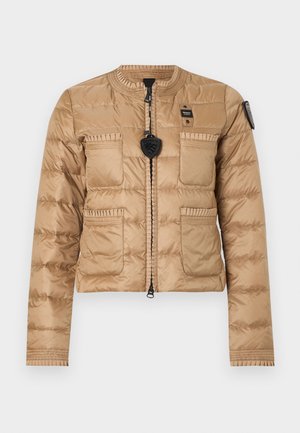 Veste matelassée marron clair avec col rond, fermeture éclair frontale, quatre poches plaquées, et écussons noirs de marque sur la poitrine et la manche.