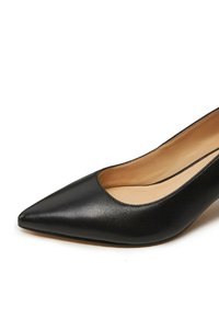 Décolleté in pelle nera con punta affusolata e scollatura bassa, caratterizzata da una texture liscia, una fodera interna beige e un tacco slanciato.