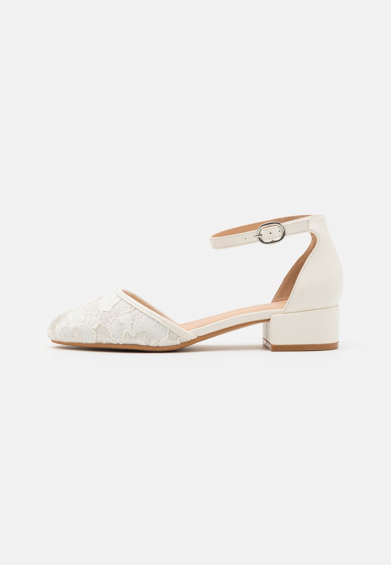 White lace ankle-strap shoe with a low, chunky heel and pointed toe design. Smooth interior lining, textured lace upper, and buckle detail.