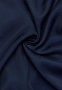 Tessuto blu navy, morbido, che si avvolge in un motivo a spirale, caratterizzato da una trama sottile e una leggera lucentezza. Adatto per diverse applicazioni tessili.