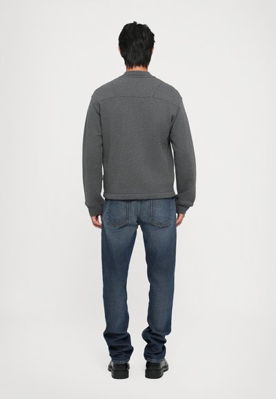 Hanorac tricotat gri cu guler rotund; asortat cu blugi din denim albastru; vedere din spate care arată un design simplu, fără modele vizibile.