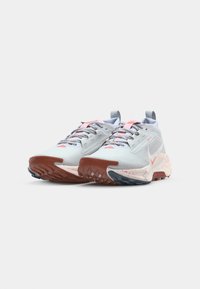 Light blue athletic shoes with textured mesh upper, pink accents, and a rugged brown and blue sole. Includes patterned laces and pull tab.