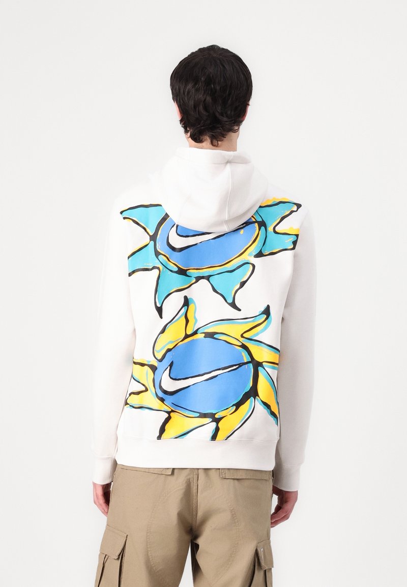 Hoodie i vitt bomull, med en stor grafisk design av en blå och gul sol på ryggen. Mjuk textur, avslappnad passform.