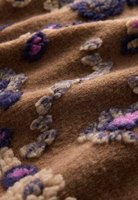 Brązowy materiał o miękkiej, puszystej fakturze, z wzorami kwiatowymi w odcieniach purpury i różu oraz beżowymi akcentami.