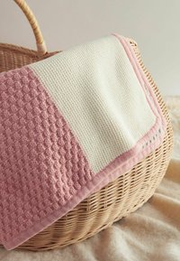 Textured throw blanket with a pink and cream color scheme, featuring a patterned weave on one side and a smooth finish on the other.
