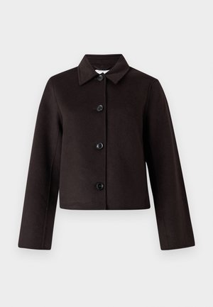 Melnā apgriezta jaka ar apkakli, ar pogu aizdari un garām piedurknēm. Izgatavota no teksturētas auduma ar redzamām šuvēm.