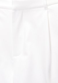 Pantalon blanc sur mesure en tissu lisse, présentant une coupe à taille plate, une seule poche latérale et des coutures cousues pour la structure.