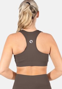 Braun Sport-BH mit Racerback-Design. Hergestellt aus strukturiertem Stoff, mit kleinem Logo auf der Rückseite. Sanfte, körpernahe Silhouette.