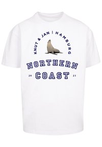 Weißes Baumwoll-T-Shirt mit einem Aufdruck eines Seehundes. Der Text lautet "Knut & Jan | Hamburg" und "NORTHERN COAST 23" in Blau. Kurze Ärmel.