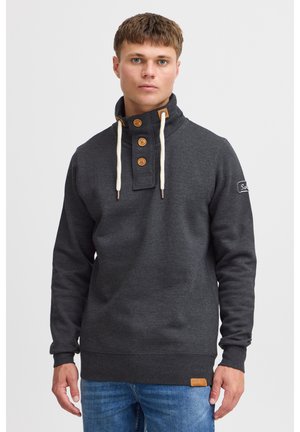 Dunkelgrauer Pullover mit hohem Kragen, Holzknöpfen und weißen Kordeln. Rippbündchen an Ärmeln und Saum, mit einem Logo-Patch am Ärmel.