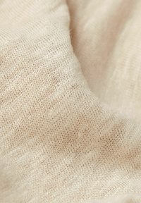 Světle béžová pletená látka s měkkou strukturou, která se vyznačuje jemným tkaním a subtilními barevnými variacemi. Hladký a lehký vzhled.