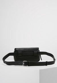 Černá kožená crossbody taška s texturovaným povrchem, obdélníkový tvar, klopový uzávěr a nastavitelný pásek s kovovou sponou.