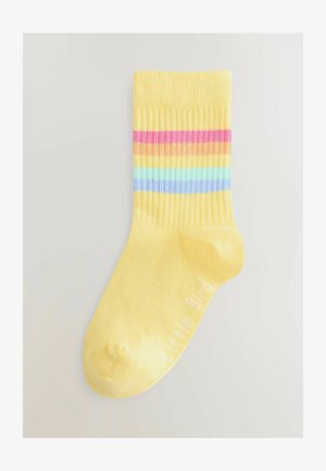 Żółta bawełniana skarpetka z prążkowaną fakturą, z poziomymi paskami w kolorze różowym, pomarańczowym, niebieskim i zielonym. Na skarpetce jest napisane "Little Bird" na biało.