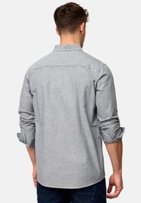 Szary koszula z guzikami, z podwiniętymi rękawami, wykonana z teksturowanej tkaniny, z kontrastującymi wewnętrznymi mankietami i detalem na karku.