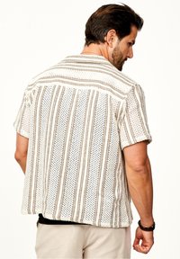 Kurzarmhemd mit weißem Grund, strukturiertem Stoff und vertikalen braunen Streifen. Es verfügt über eine entspannte Passform und ein dezentes Punktemuster.