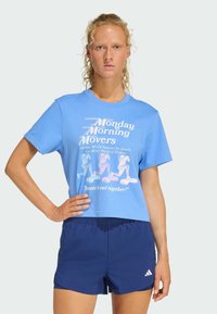Lyseblå bomulds crop t-shirt med hvid grafisk tekst og løbende figurer. Sammen med marineblå shorts, der har elastisk talje og logo.