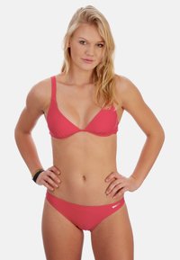 Rosa Bikini mit einem dreieckigen Cup-Design und dünnen Trägern. Der Unterteil hat einen tief sitzenden Schnitt mit einem Logo-Akzent. Glatte Textur.