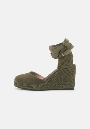 Espadryle na klinie w kolorze oliwkowej zieleni z teksturowaną tkaniną na cholewce, zaokrąglonym noskiem i plecioną podeszwą z juty. Pasek wokół kostki wiązany z tyłu.