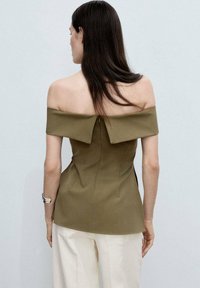 Olivno zelena bluzica na jedno rame sa strukturiranim dizajnom, koja sadrži srednji zip na leđima i elegantno padajuću drapiranu tkaninu.