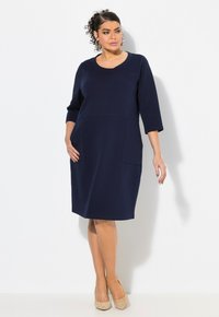 Navyblaues Kleid mit rundem Ausschnitt, dreiviertel Ärmeln und Fronttaschen. Hergestellt aus weichem Stoff, hat es eine entspannte A-Linie-Silhouette.