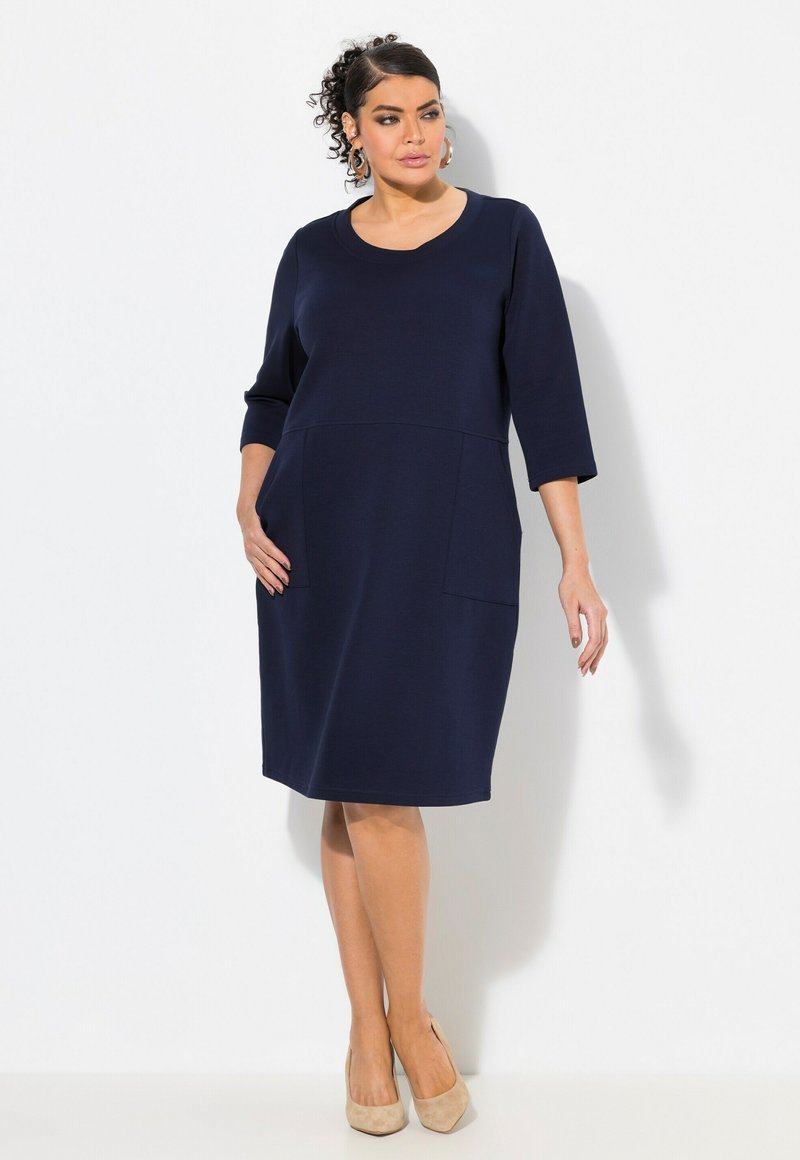 Navyblaues Kleid mit rundem Ausschnitt, dreiviertel Ärmeln und Fronttaschen. Hergestellt aus weichem Stoff, hat es eine entspannte A-Linie-Silhouette.