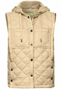 Beige prošívaná vesta s kapucí, vybavená dvěma předními kapsami, cvoky a hladkým povrchem. S nastavitelnými šňůrkami na kapuci.