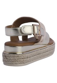 Sandalias de plataforma con una correa metálica dorada, plantillas acolchadas de color marrón y suela texturizada envuelta en yute. Cuenta con un cierre de hebilla.