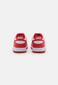 Adidași roșii cu accente albe, superior din piele și plasă, guler căptușit și talpă din cauciuc. Dispune de logo-ul "NIKE" în spate.