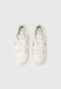 Hvide Nike sneakers med overdel i læder og ruskind, perforeret tå, polstret krave og signatur swoosh i grå på hver side.