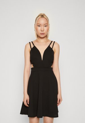 Robe noire avec un décolleté en V profond, des bretelles fines, des découpes latérales et une jupe évasée. Fabriquée en tissu lisse avec une taille cintrée.