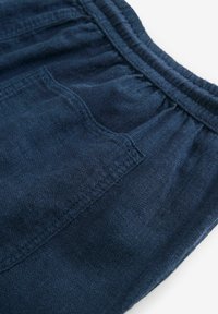 Mørkeblå shorts lavet af blødt stof, med elastisk talje og en forlomme, samt detaljer med struktureret vævning.
