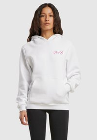 Felpa bianca con cappuccio e grafica a cuore rosa sul petto, dotata di tasca a canguro e polsini a costine per una vestibilità aderente.