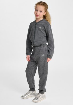 Szary rozpinany sweatshirt zestawiony z dopasowanymi spodniami dresowymi, z elastycznymi mankietami i pasem. Srebrne sneakersy dopełniają ten strój.